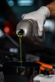 mechanic pouring oil into funnel during oil change