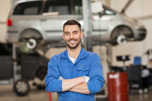 auto mechanic standing in front of a car in an auto repair shop