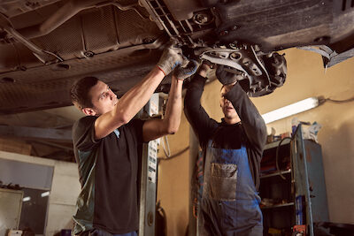 Transmission checking and repairing. Two proficient auto mechanics working with lifted vehicle. auto mechanics checking the car transmission