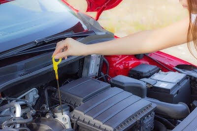 teen checks engine oil levels in her car