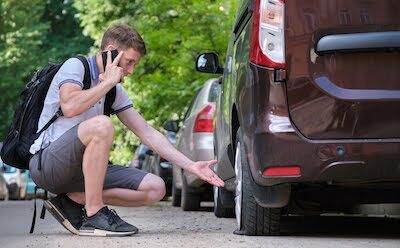 teen making a phone call regarding his car's flat tire