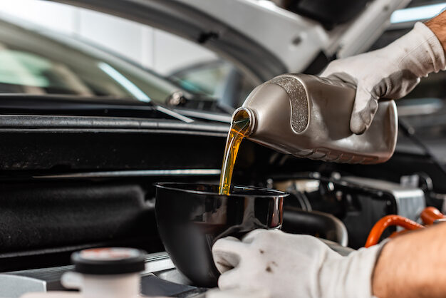 partial view of mechanic pouring motor oil at car engine partial view of mechanic pouring motor oil at car engine